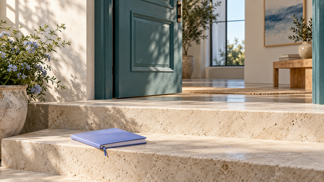 Ivory stone steps and a periwinkle notebook beside a partially open teal door.